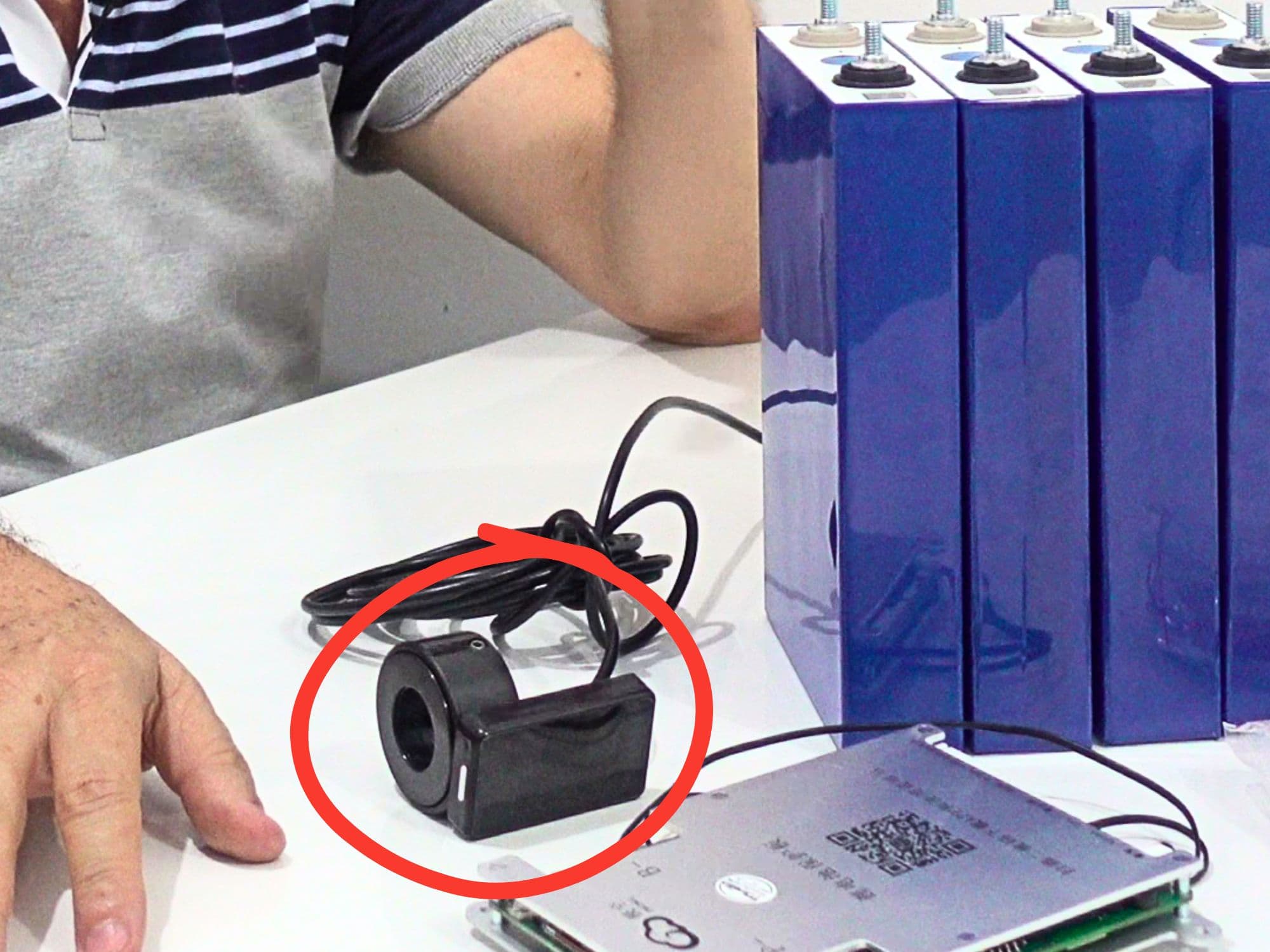 Placa de BMS ao lado de um pack de células LiFePO4 prismáticas, com o sensor de corrente (shunt) em destaque